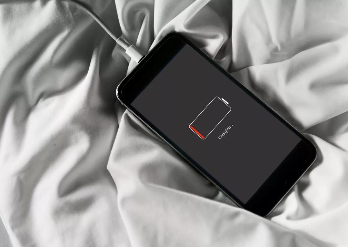Греется и разряжается телефон. Подзарядка для смартфона. мобильник разрядился. разряженный телефон. телефон на столе.