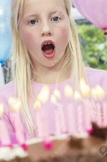 Feliz mujer rubia niño soplando las velas de la torta de cumpleaños 