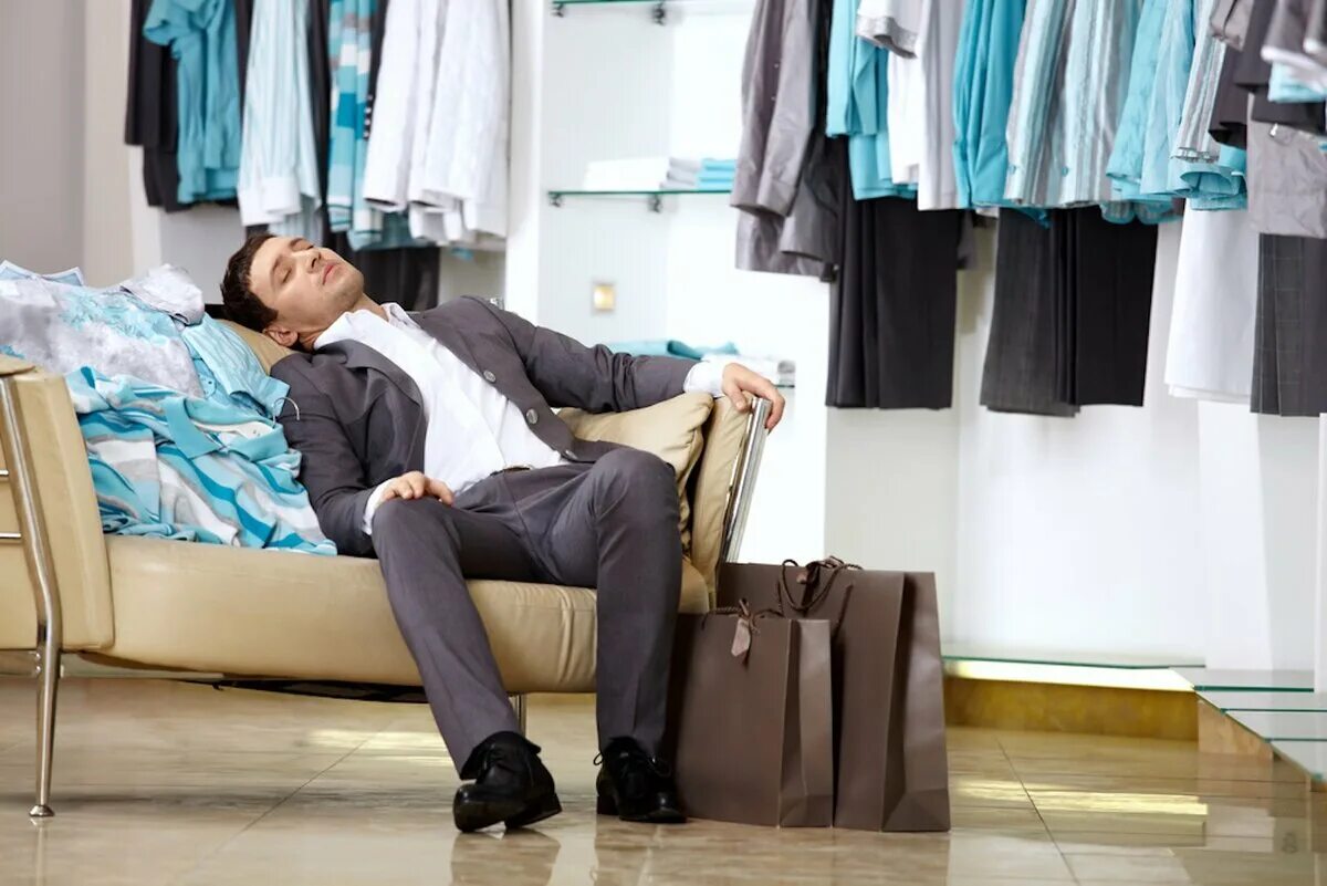 Мужчина устал от шопинга. Уставший мужчина в магазине. Мужчина в магазине одежды. Мужик уснул в магазине. Медленно одевается