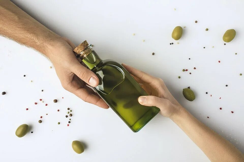 Масло быстро окисляется. Оливковое масло. бутылка в руке. бутылка оливкового масла. стеклянная бутылка в руке.