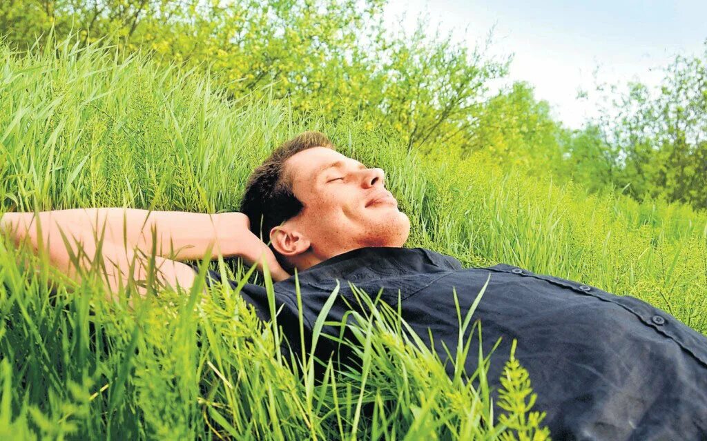 Где можно расслабиться. Человек лежит на траве. Лежит на траве. Расслабление на природе. Мужчина лежит на траве.