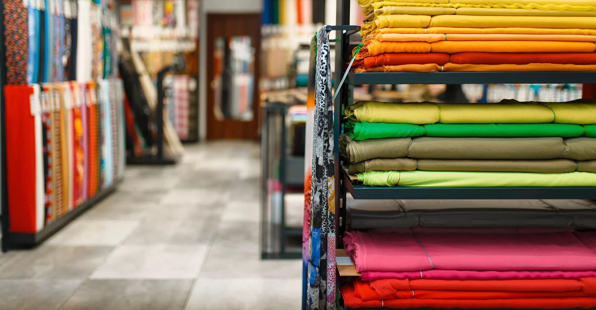 Ткани на полке. Оптовая торговля текстильными изделиями. Текстильное производство. Рулоны ткани на складе. Склад трикотажа.