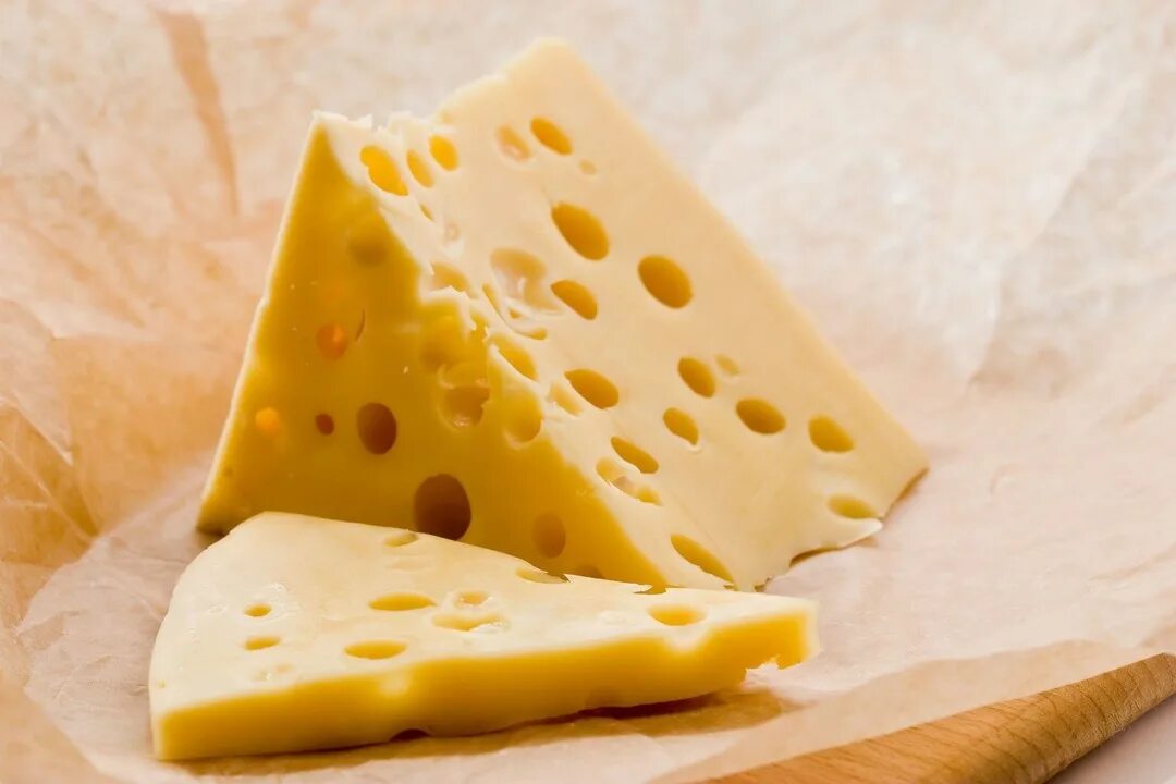 Кусок сыра. Сыр Маасдам Гауда. Дырки в сыре. Большой кусок сыра. Сыр с крупными дырками.