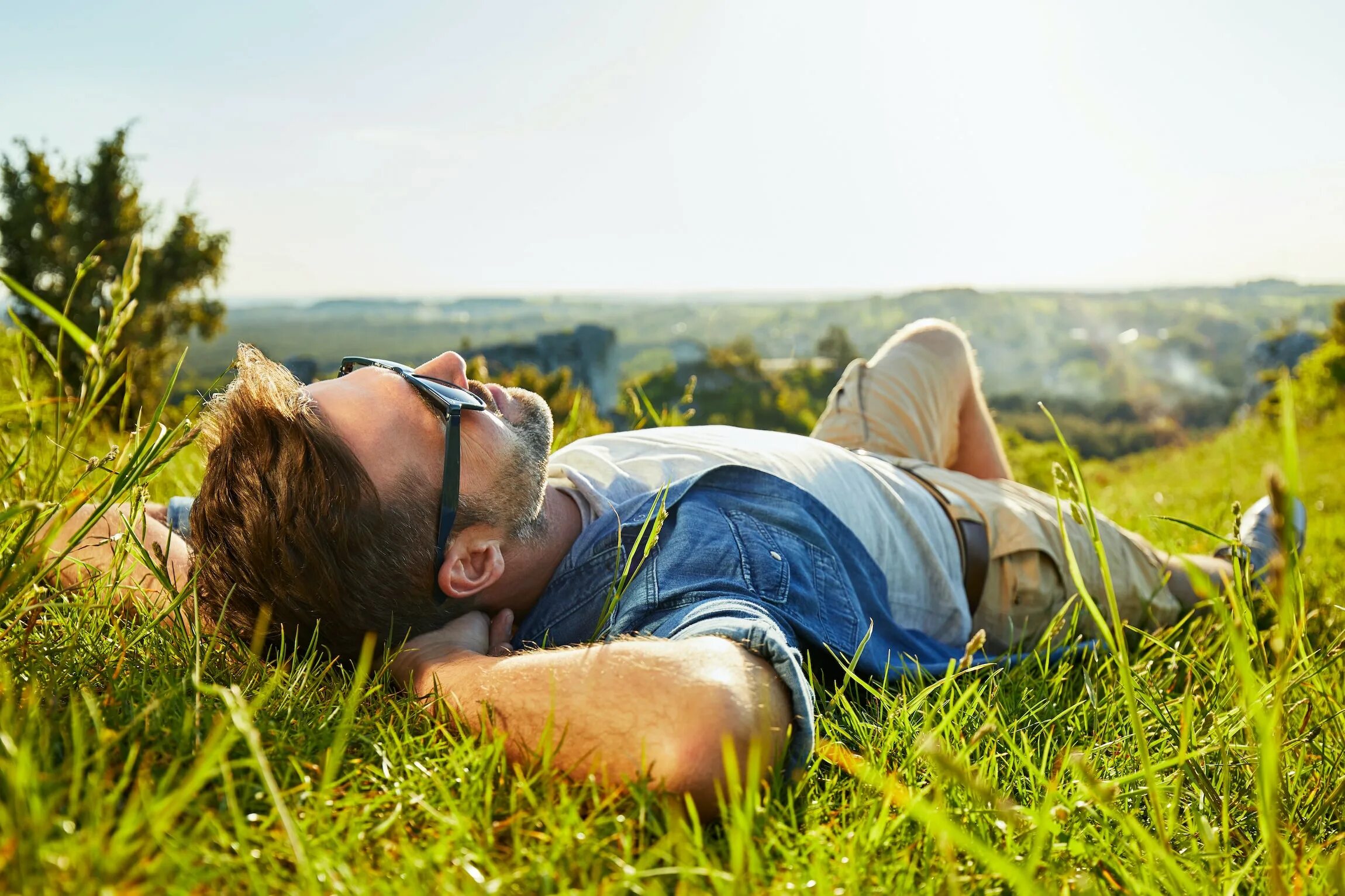 Enjoy rest. Мужчина лежит на траве. Парень лежит на траве. Человек лежит на природе. Человек отдыхает.