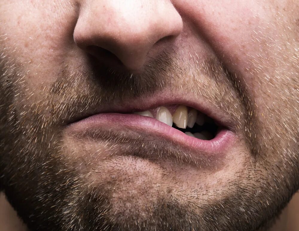 Мужчина скрипит зубами. Злые зубы. Сильно скриплю зубами