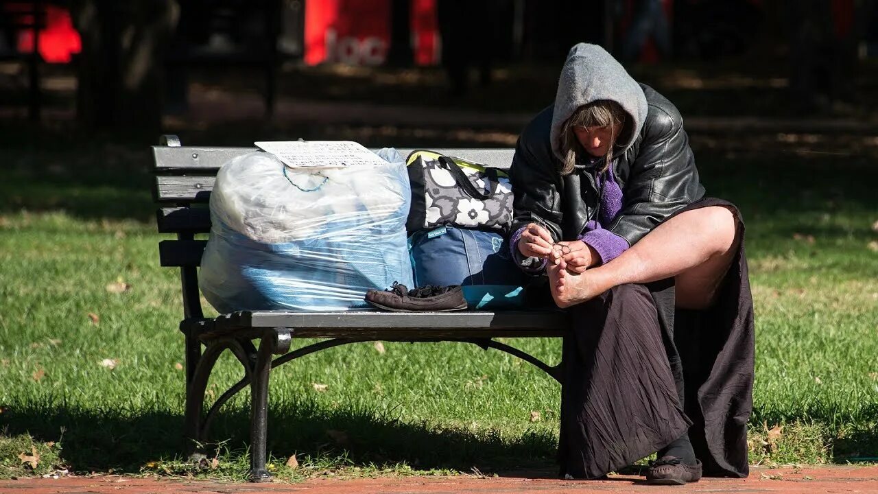 Homeless women. The face of a homeless woman in a Jacket sitting on a Tree.