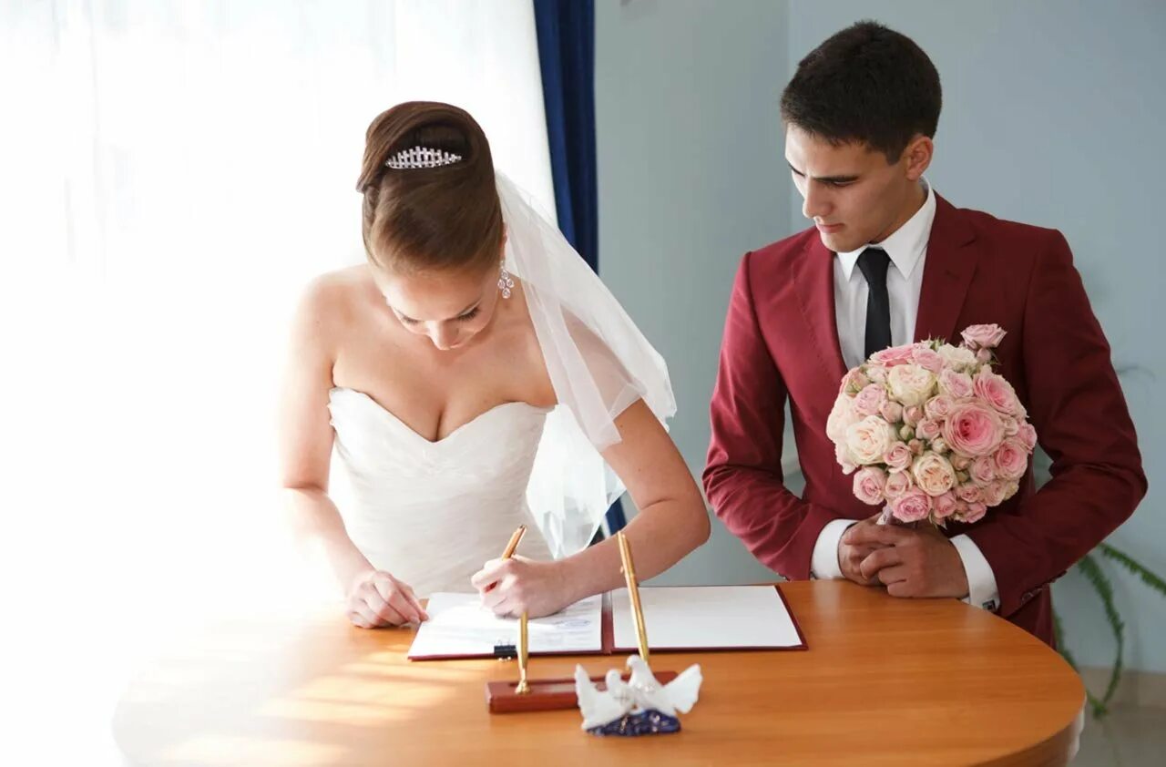 Запрет свадеб. Пара в ЗАГСЕ. Жених и невеста расписываются. Жених и невеста в ЗАГСЕ. Свадьба ЗАГС жених и невеста.