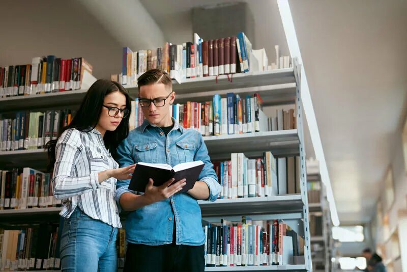 Книга юноша и девушка. Парень и девушка в библиотеке. мужчина в библиотеке. мужчина и женщина в библиотеке. студенты в библиотеке.
