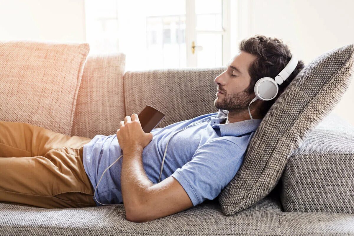 Аудио о жизни слушать. Человек отдыхает. Мужчина отдыхает на диване. Человек в наушниках. Человек с наушниками.