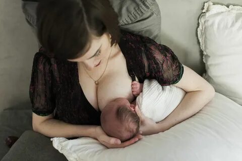 High angle view of mother breastfeeding newborn son while sitting on bed at...