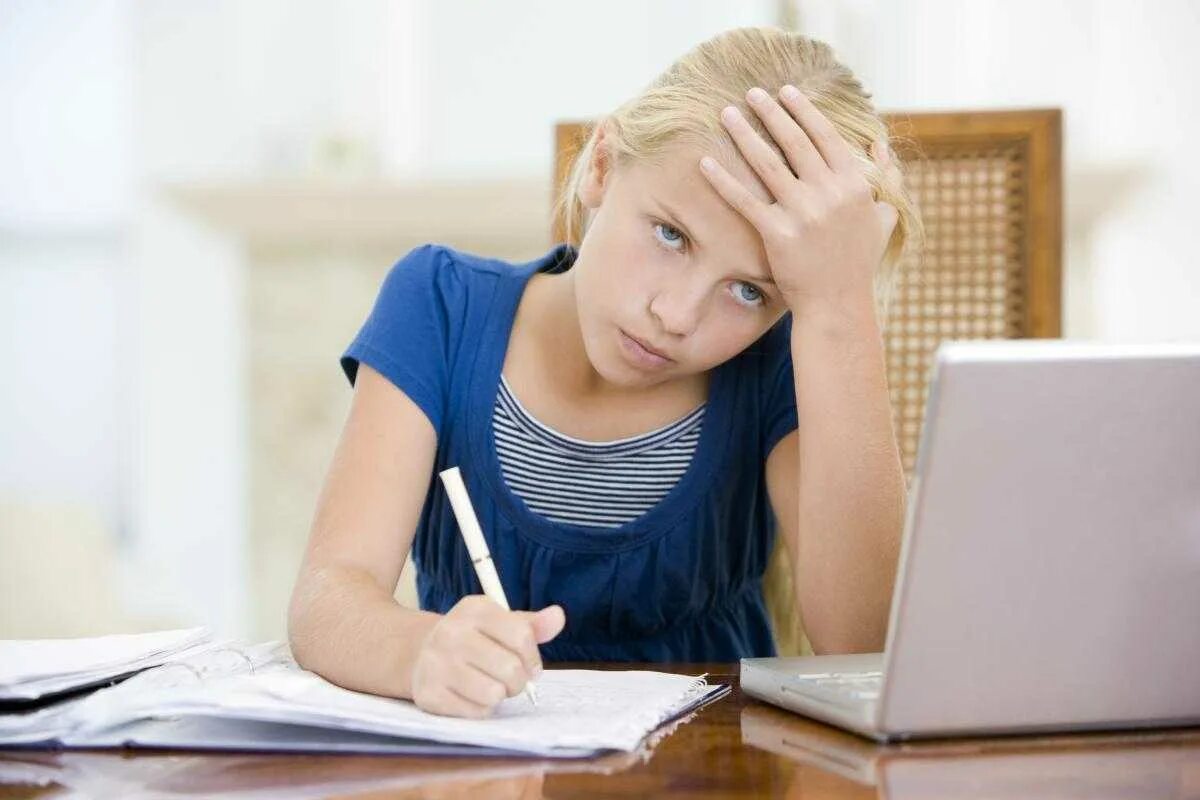 Ребенок учит уроки. Девочка делает уроки. Ребенок за уроками. Ребенок выполняет домашнее задание.