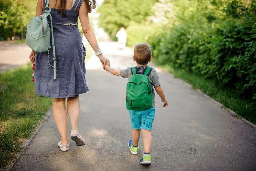 Отпускать ли детей в школу. Дети на прогулке. Мама с ребенком идут. Мама ведет ребенка за руку. Прогулки с малышом.
