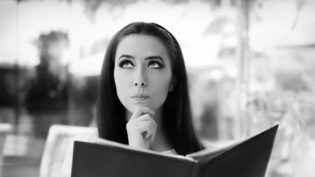 Девушка смотрит на свои руки. С меню ресторан девушка. девушка держит меню в ресторане. девушка читает меню. читающий ресторан.