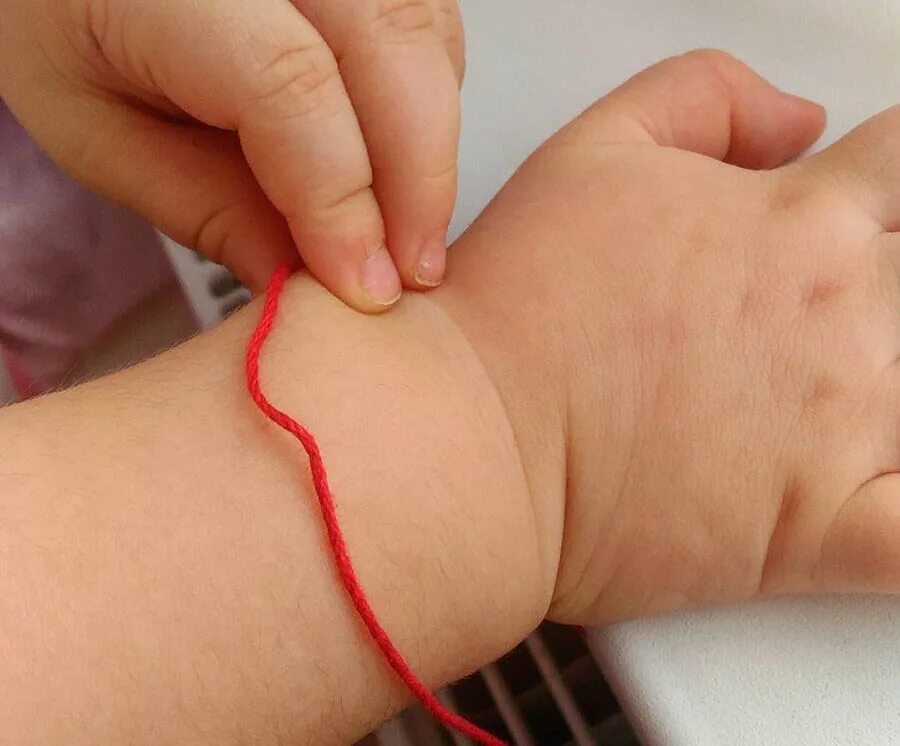 Красная нитка от сглаза для ребенка. Красная нить на запястье ребенка. Красная нитка на руке. Красная шерстяная нитка. Красная нить на запястье ребенку.