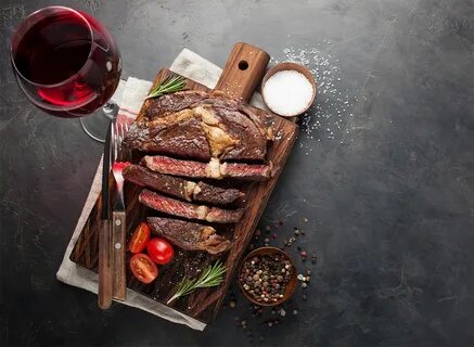 sliced steak with glass of red wine and salt in pinch bowl. 