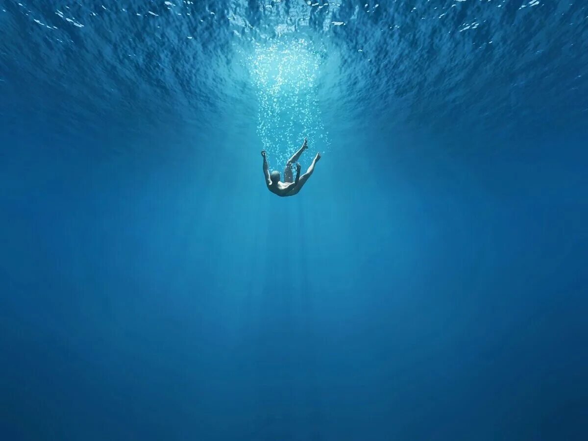Тонущий человек. Человек тонет в океане. Падение в воду. Тонущий человек под водой.