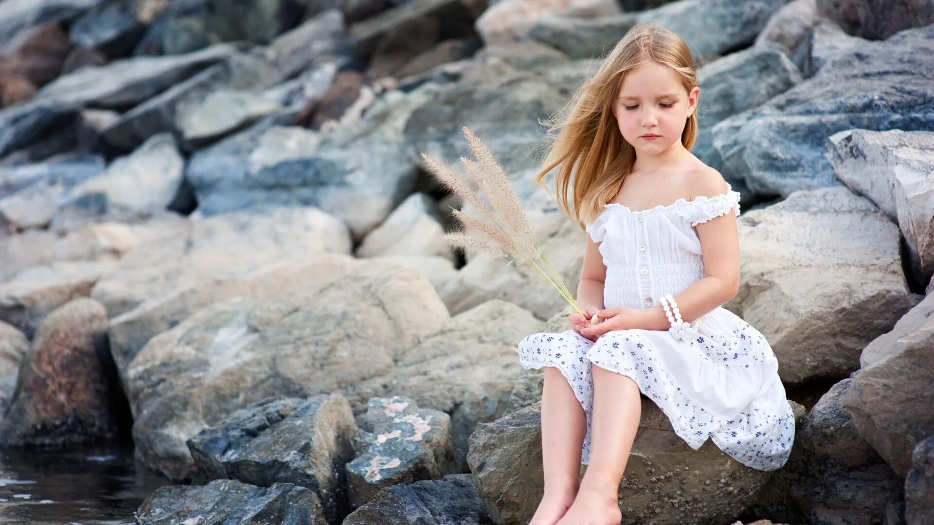 Devochki. Маленькая девочка сидит на Камне. Девочка в платье сидит. Девочка с камнем. Девочка на берегу.