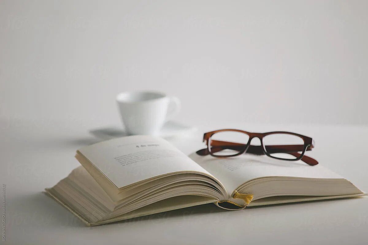 Раскрытая книга лежит на столе. Книга и очки. Книга Минимализм. Очки на столе. Стопка книг и очки.