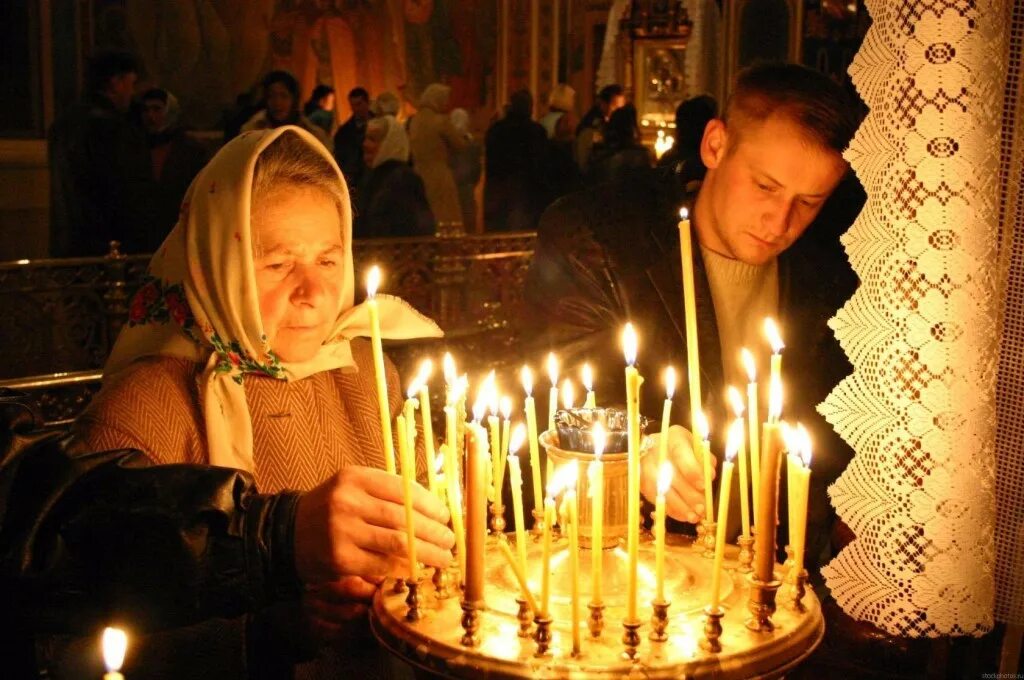 Мужчина ставит свечу. Люди в церкви. Свечи в церкви. Зажженная свеча в церкви. Человек молится в храме.