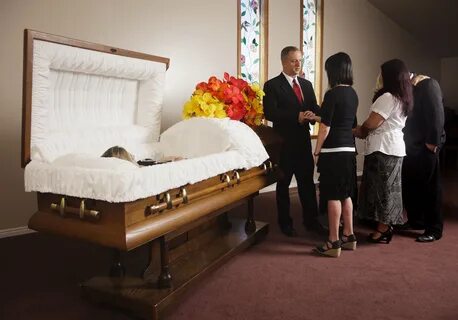 A receiving line of guests next to the casket at a funeral in a funeral hom...