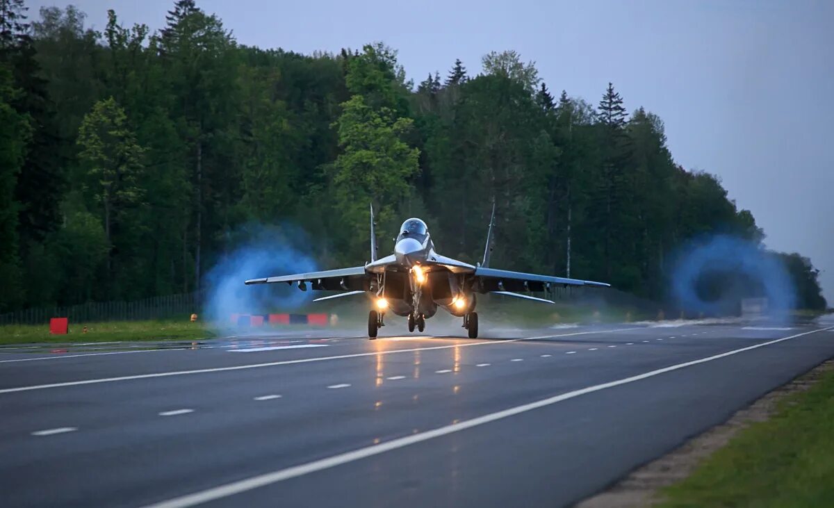 Посадка истребителя. Су-27 на посадке. Военный самолет на взлетной полосе. Истребитель на дороге. Истребитель над дорогой.