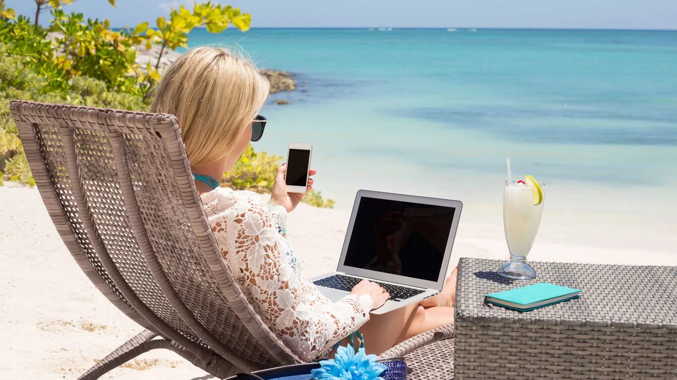 Заработать путешествуя. Девушка с ноутбуком на берегу моря. Удаленная работа. С ноутбуком на море. Девушка с ноутбуком на море.