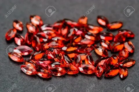 Large pile of rich red marquise cut rubys on black stone. 