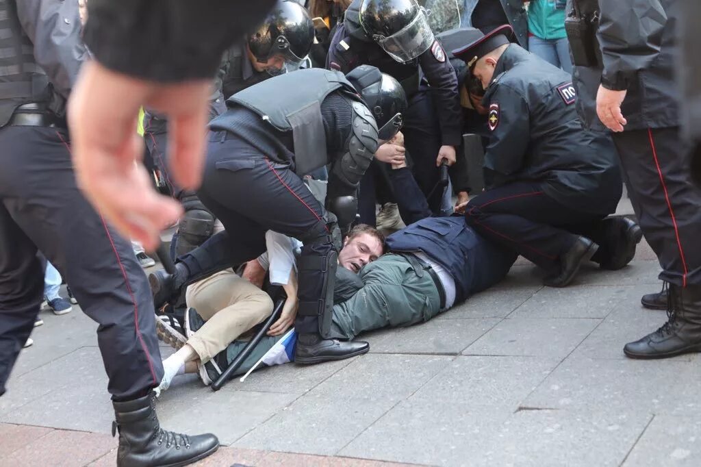 Полицейский избивает дубинкой. Разгон демонстрантов в москве. Избиение милицией. Избиение милицией. Задержания на митинге в москве.
