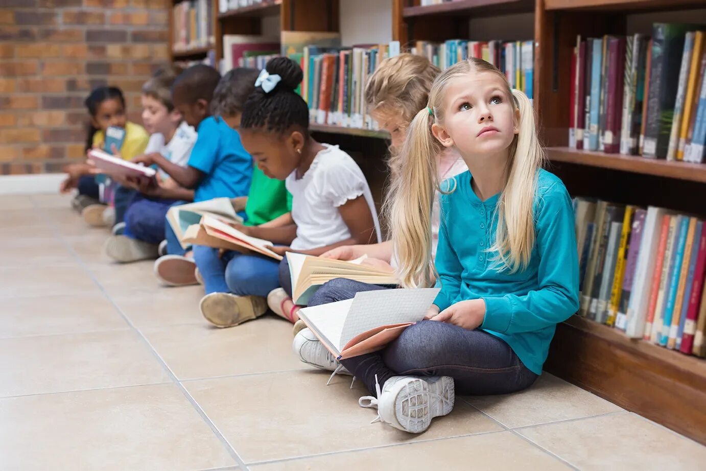 Дети сидят в библиотеке. Ученики сидят на полу. Sitting pupil. Дети в библиотеке сидящие по кругу фото.