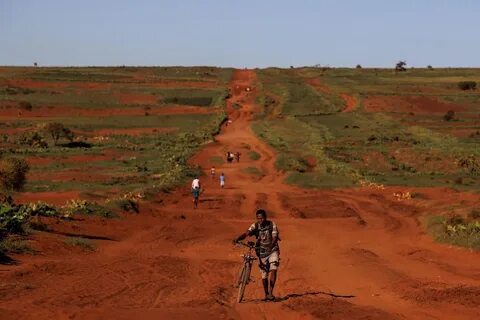 A man pushes his bike along the RN13 road. 
