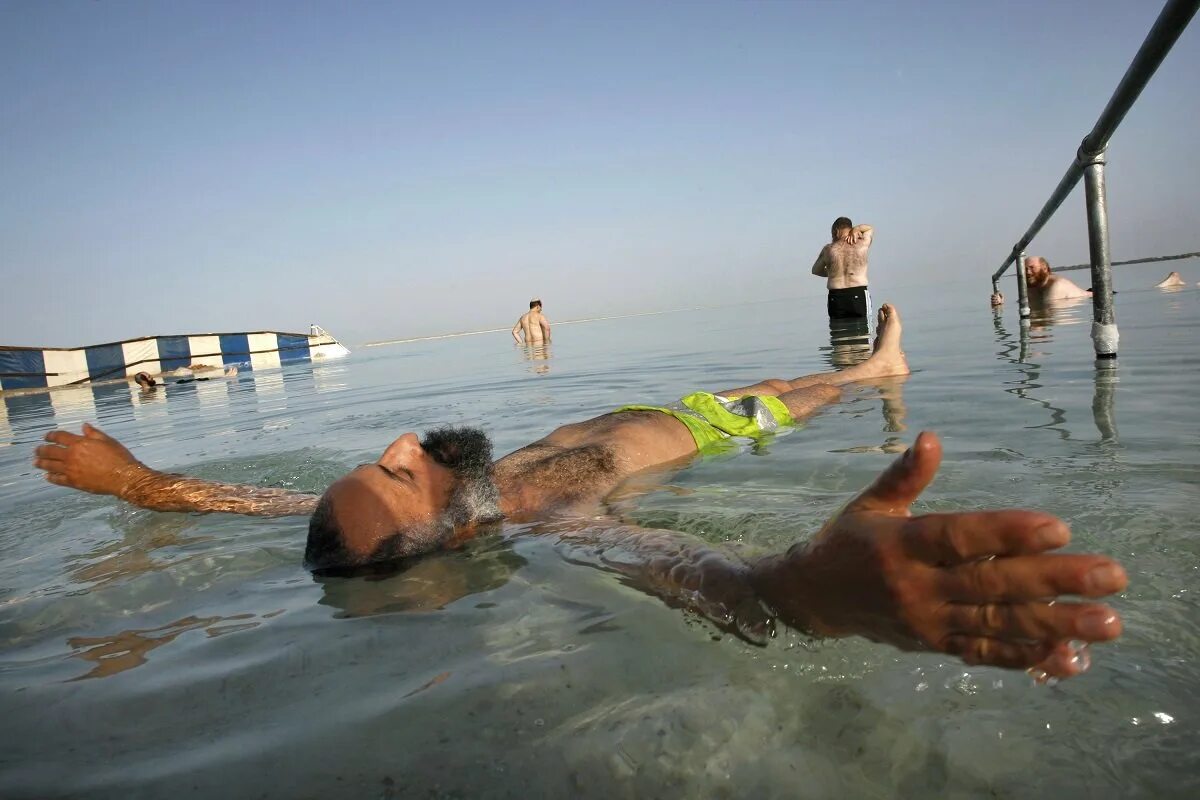 Мертвое море человек на воде. Мертвое море купание. Мертвое море люди. Мёртвое море люди купаются.