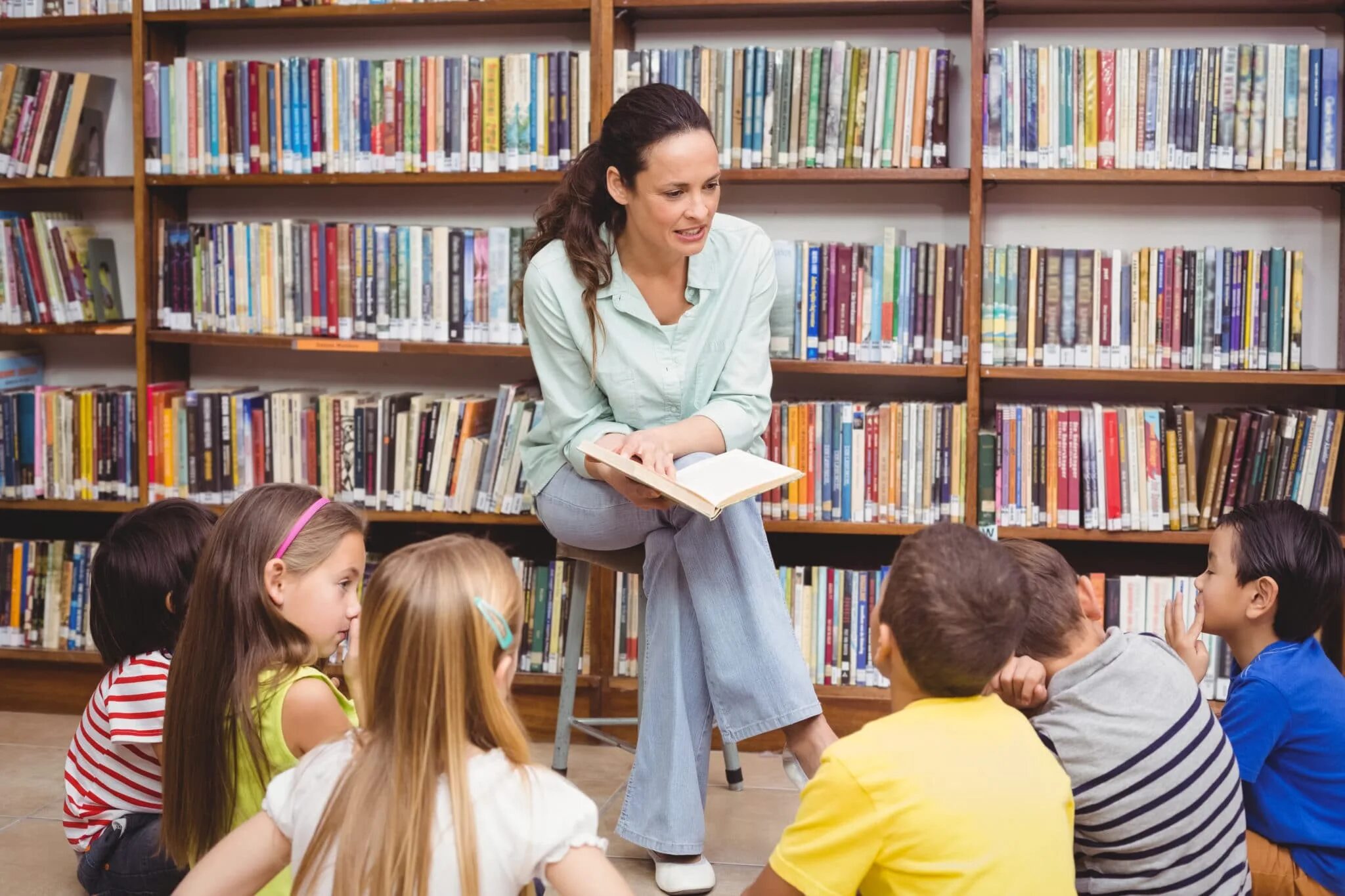 Читаем слушаем читаем. Дети в библиотеке. Библиотекарь для детей. Библиотекарь детской библиотеки. Школьник читает книгу.