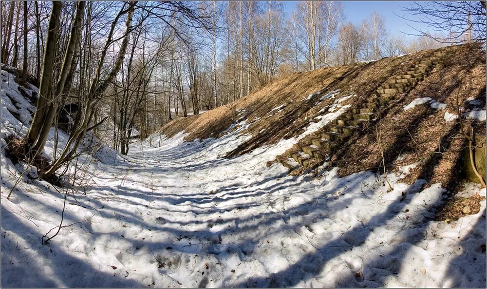 Снег сходит с пригорков веселыми ручейками. Таяние снега на склонах. Овраг зимой. Склон оврага. Овраг весной.