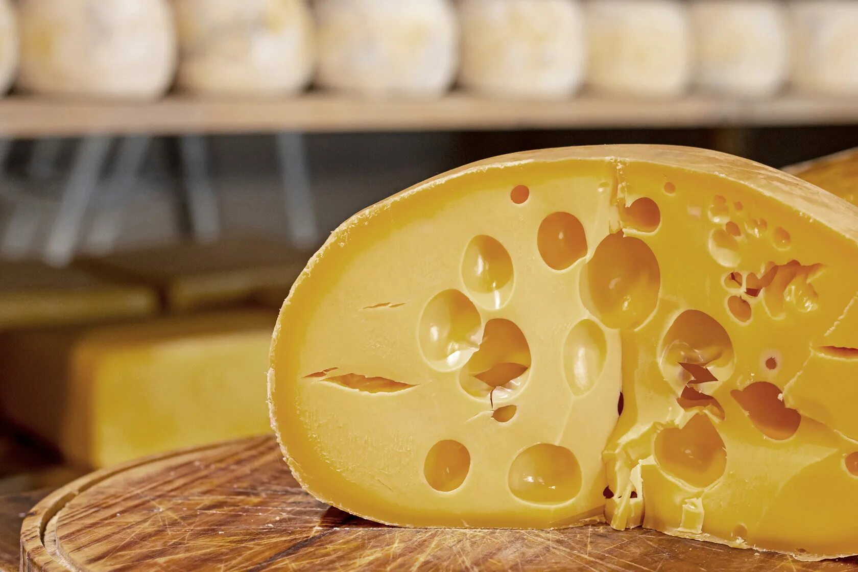 Вкуснейший сырный. Швейцарский сыр с дырками. Желтый сыр. Головка сыра с дырочками. Кусочек сыра.