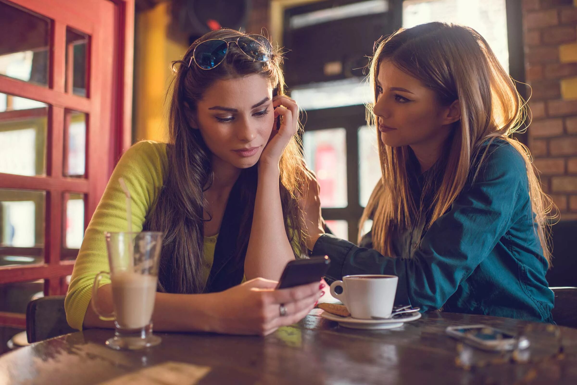 Подруга сидит в телефоне. Две подруги в кафе. Подруги в кофейне. Подруги беседуют в кафе. Две девушки в кафе.