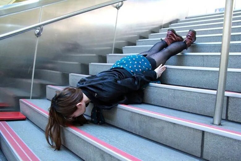 Приниматься вниз. Человек лежит на лестнице. Девушка лежит на ступеньках. Девушка лежит лицом вниз. Человек на ступеньках.
