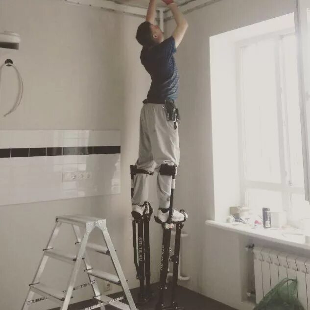 Уперся в потолок. Высокие потолки и человек. Самодельные строительные ходули. Затопили натяжной потолок. Высокий человек до потолка.