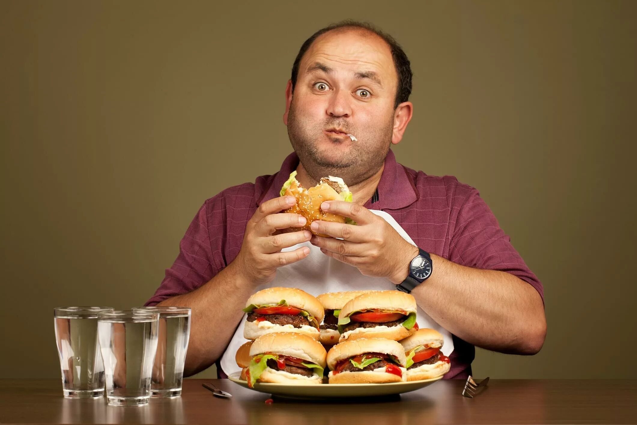 Переедание. Человек ест гамбургер. Человек с едой. Мужчина и много еды. Он хочет ее съесть 32