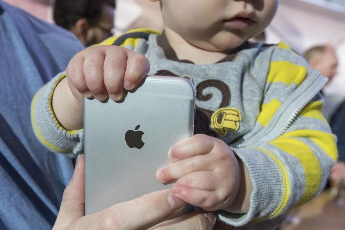 Ребенок с айфоном. Малыш с айфоном. Детский айфон в руках ребёнка. Школьник с айфоном. Можно ли ребенку айфон