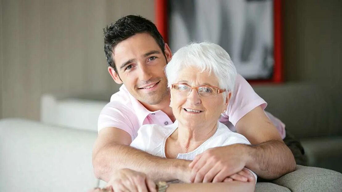 Бабушка с ребенком. Бабушка надела на ноги игрушки внука. Внук в спальне бабушки. Заправленная кровать старинная. Внук в спальне бабушки.