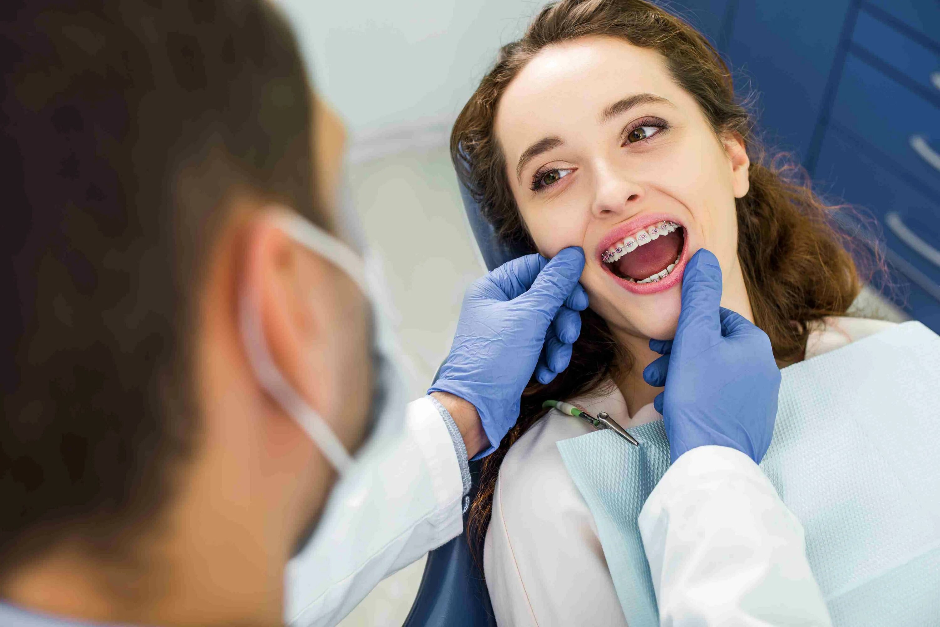 Девушка с брекетами. Девушка с брекетами у стоматолога. Женщина на приёме у усамотолога. Консультация ортодонта.