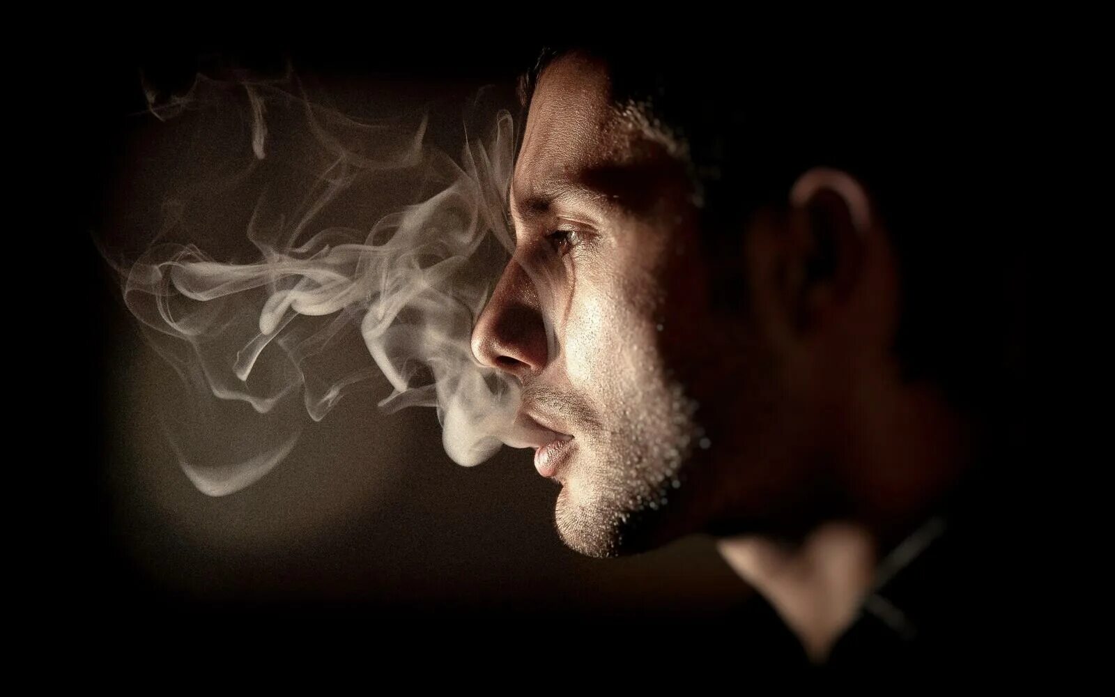 Дымом печали. Задумчивый мужчина. Парень курит. Человек выдыхает дым. Задумчивый мужчина с сигаретой.