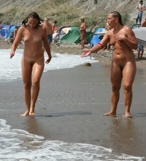 Mutter und Tochter spielen nackt am FKK Strand. 