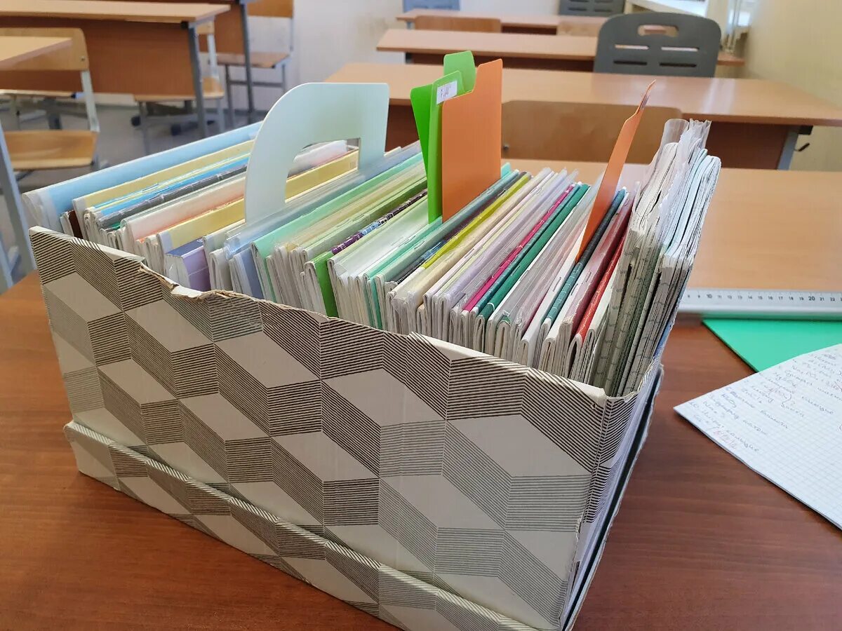 на столе учителя лежали тетради