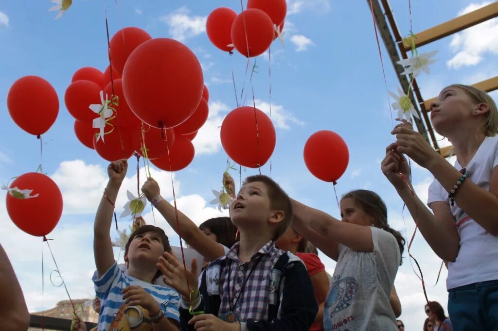 Ученик с шарами. Дети запускают воздушные шары. Дети запускают шарики в небо. Люди запускающие воздушные шары. Праздник с воздушными шарами.