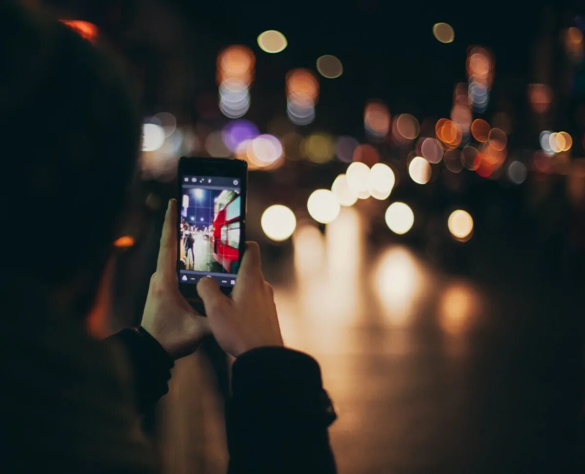 Смартфон ночью. Смартфон в темноте. Человек фотографирует на телефон. Фотосессия ночью с телефоном.