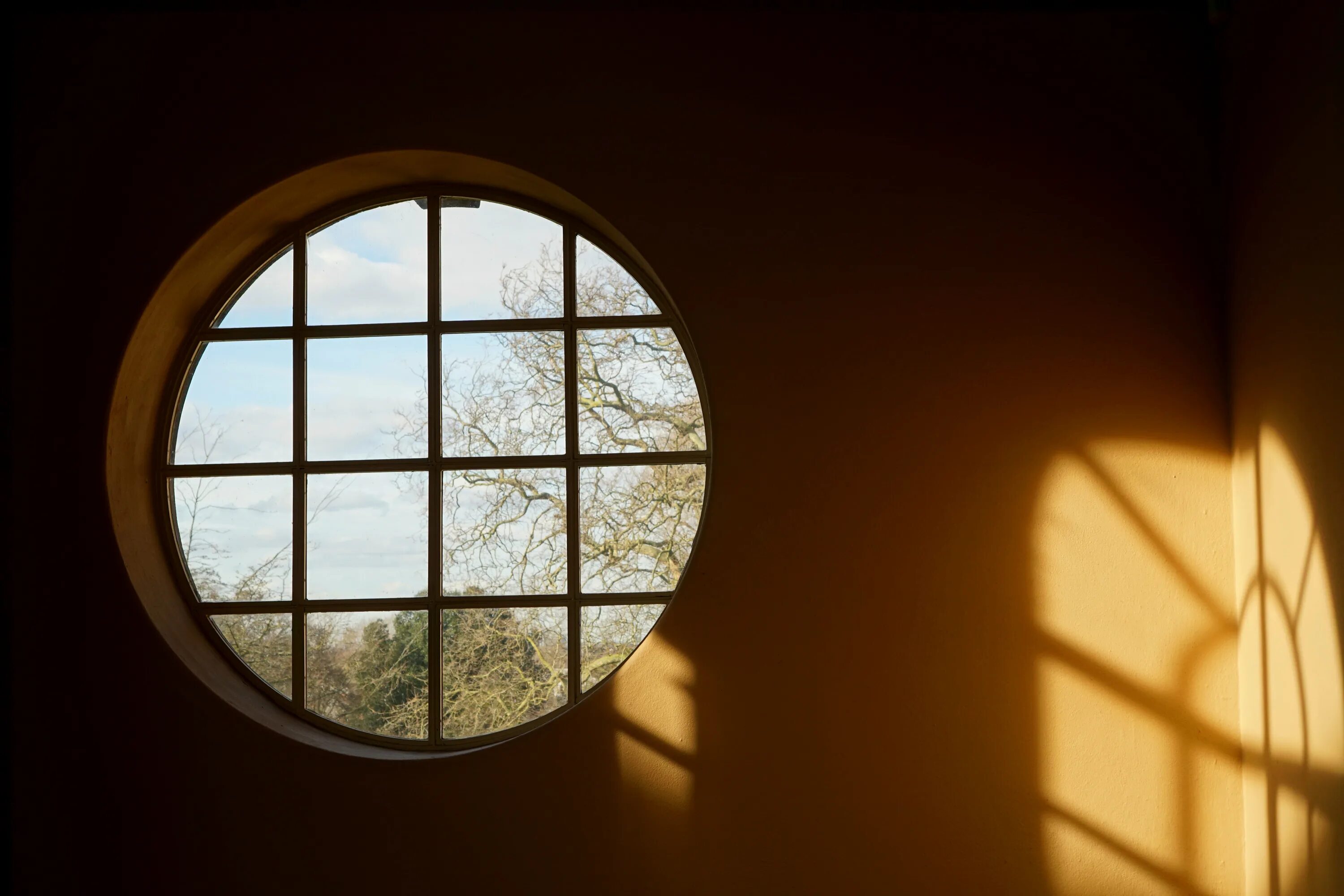 В окнах отражается солнце. Тень от окна. Круглое окно. Круглое панорамное окно. Круглое окно в стене.