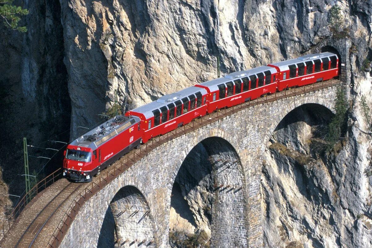 Поезд на мосту. Поезд из тоннеля. Поезд выезжает из тоннеля. Красивые железнодорожные мосты в горах.