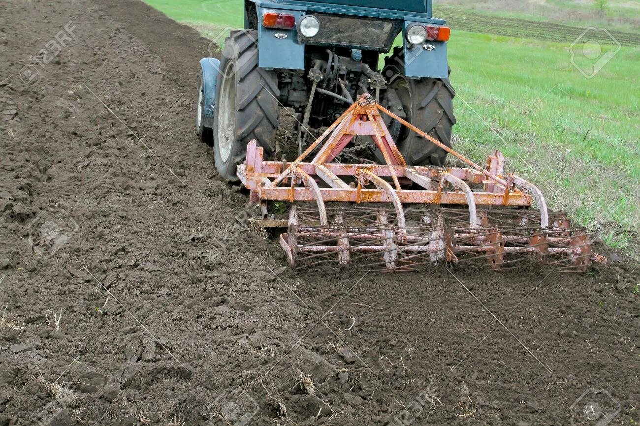 Техника для обработки земли. Трактор боронит землю железными зубьями бороны. Боронование почвы трактором. Борона для трактора. Вспашка земли плугом.