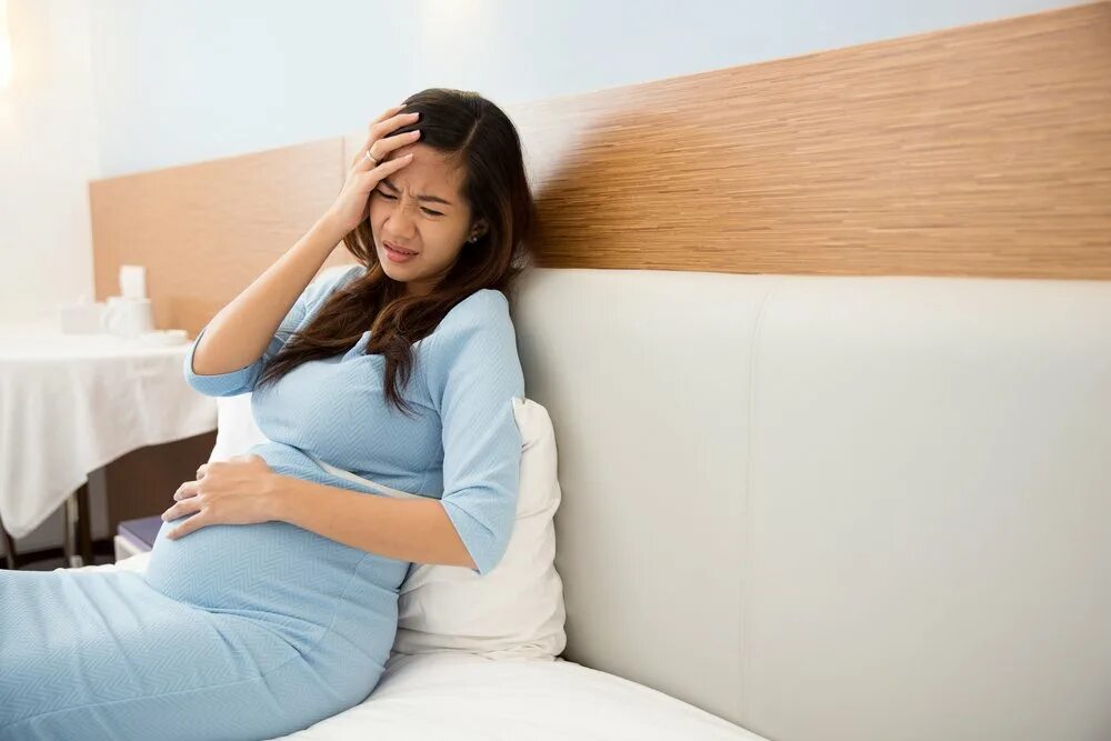 Беременность приходящая. Боли у беременных женщин. Беременная азиатка. Самочувствие беременной. Больная беременная женщина.
